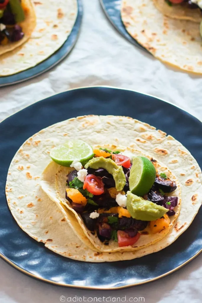 Ein Teller mit leckeren gegrillten Gemüsetacos, gefüllt mit Mais, Zucchini, Tomaten, Zwiebeln und frischem Koriander, garniert mit Limettenscheiben.
