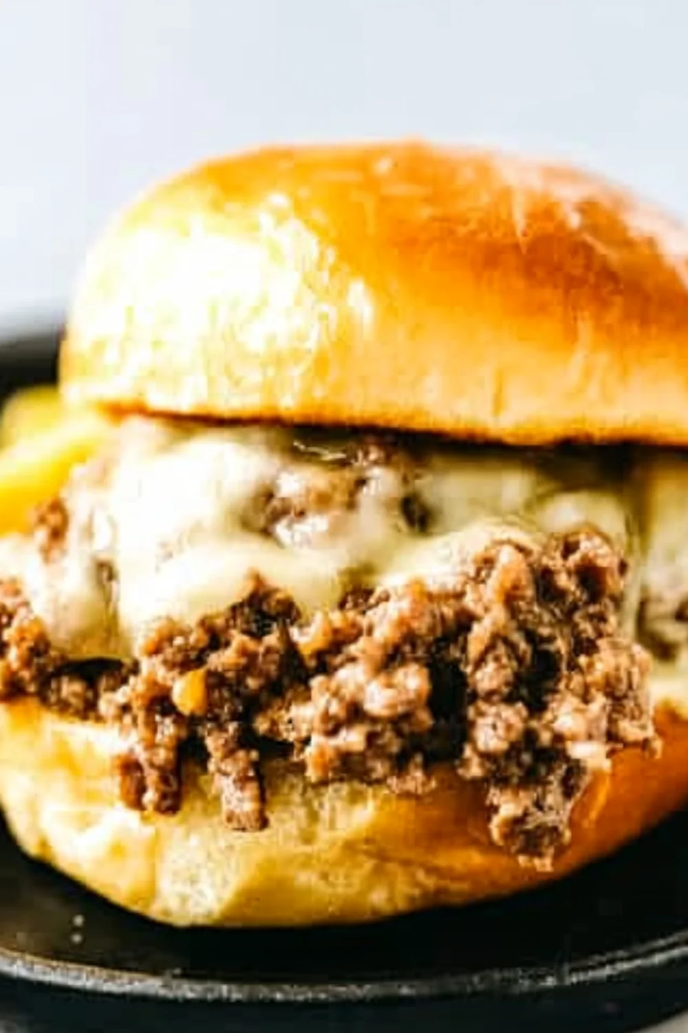 Nahaufnahme eines Sloppy Joe Burgers mit würzigem Hackfleisch und geschmolzenem Käse in einem weichen, goldbraunen Brötchen.