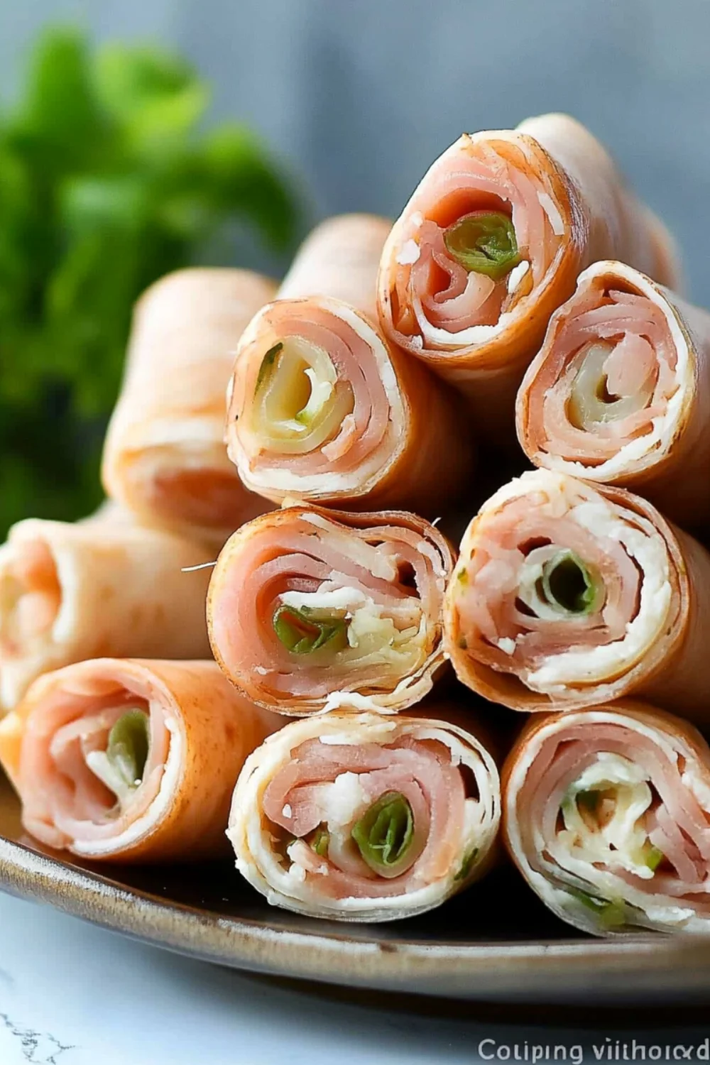 Nahaufnahme von leckeren Schinkenröllchen, die mit Frischkäse und geschnittenen Gurken gefüllt sind.
